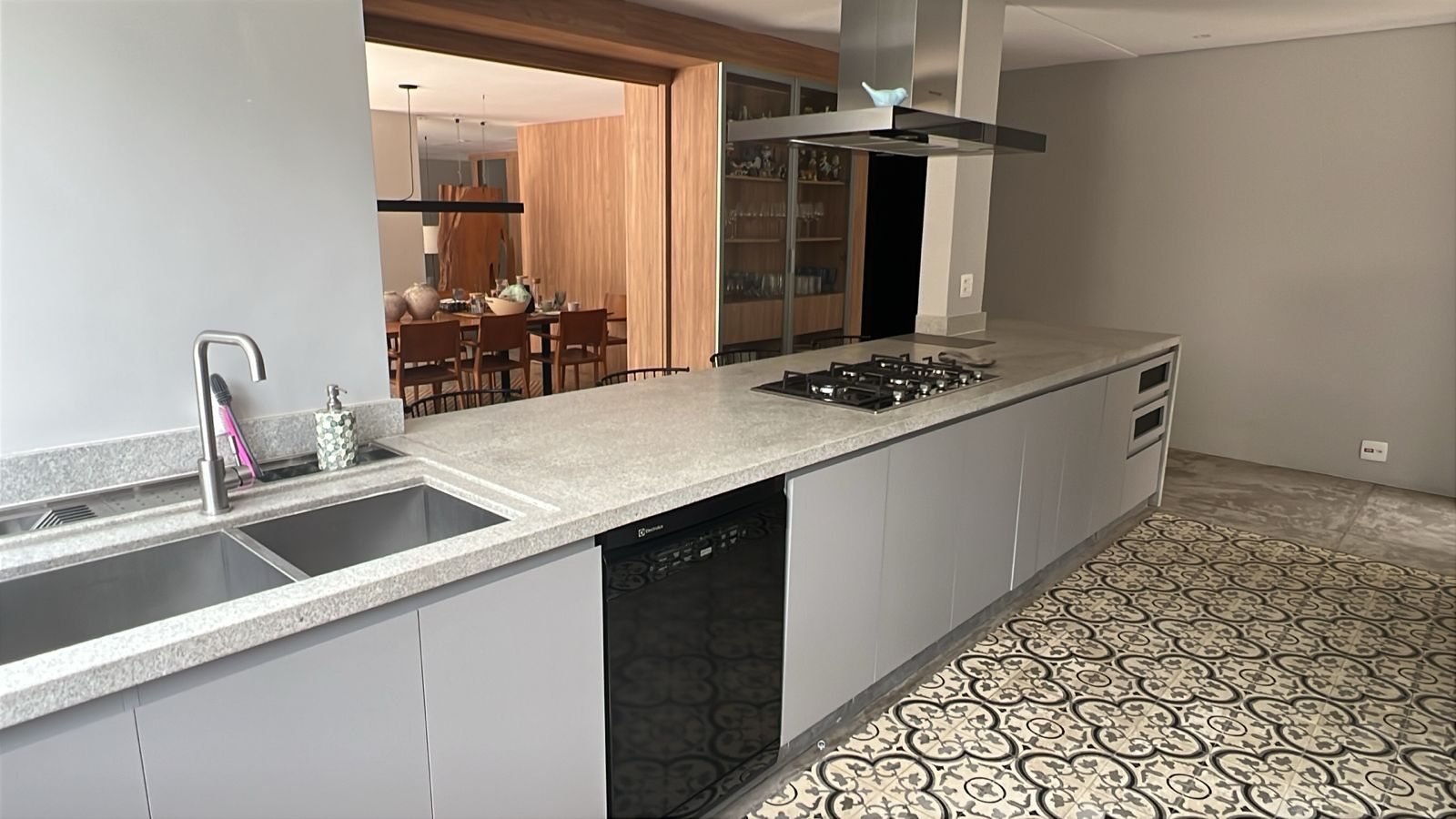 Cozinha com bancada contínua em granito cinza, cuba dupla e cooktop embutido