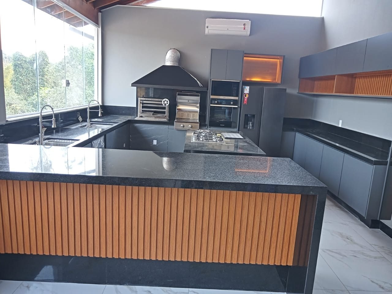 Bancada em granito preto com cuba, cooktop e balcão com laterais em esquadro