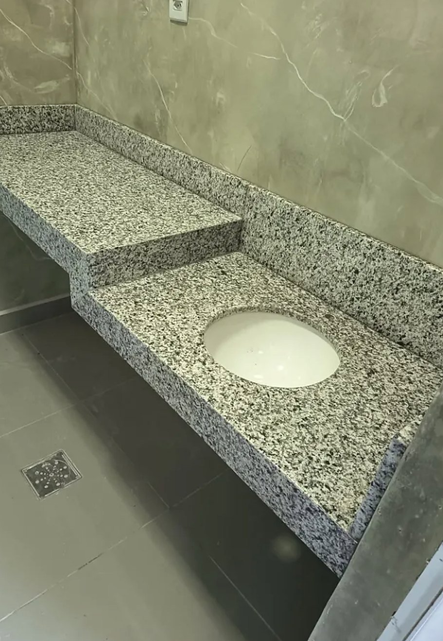 Bancada em granito com lavatório, rodabanca e acabamento em dois níveis