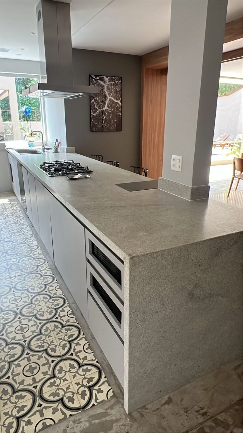 Bancada em granito cinza com lateral em cascata, cooktop e cuba embutida