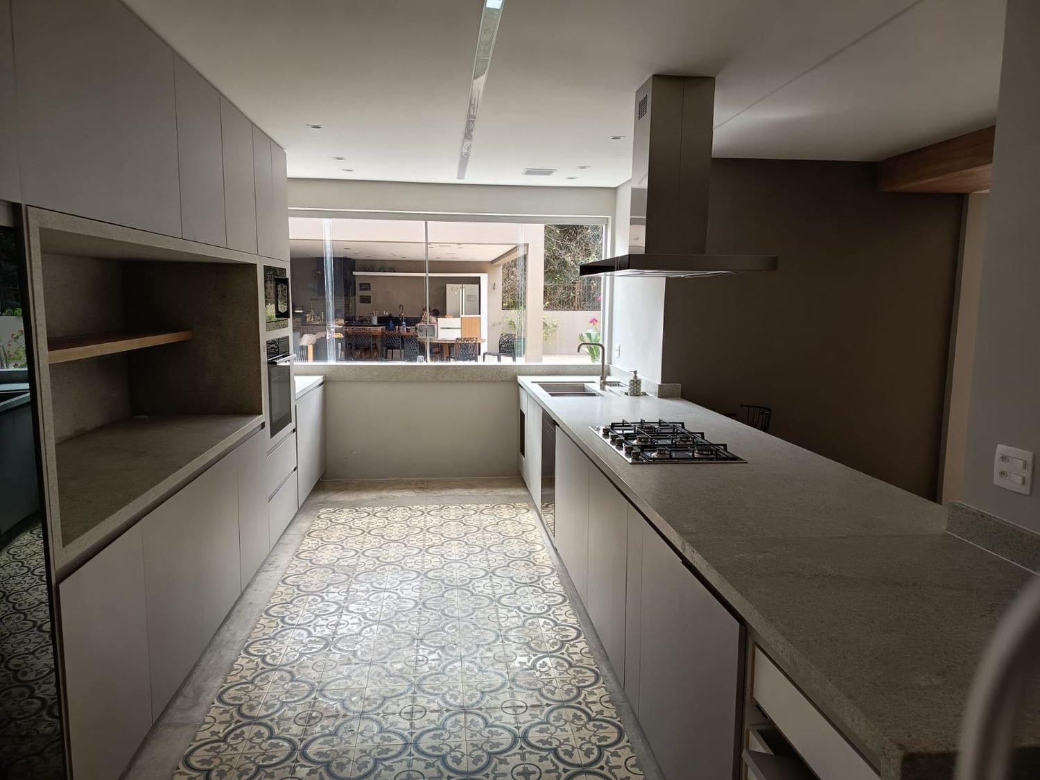 Cozinha com bancada contínua em granito cinza, cuba dupla e cooktop embutido