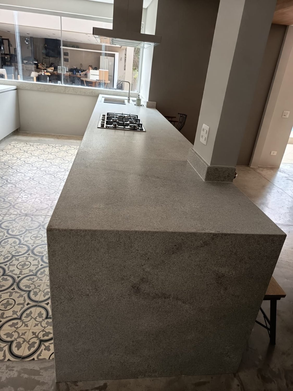Bancada de cozinha em granito cinza com lateral em cascata e cooktop embutido