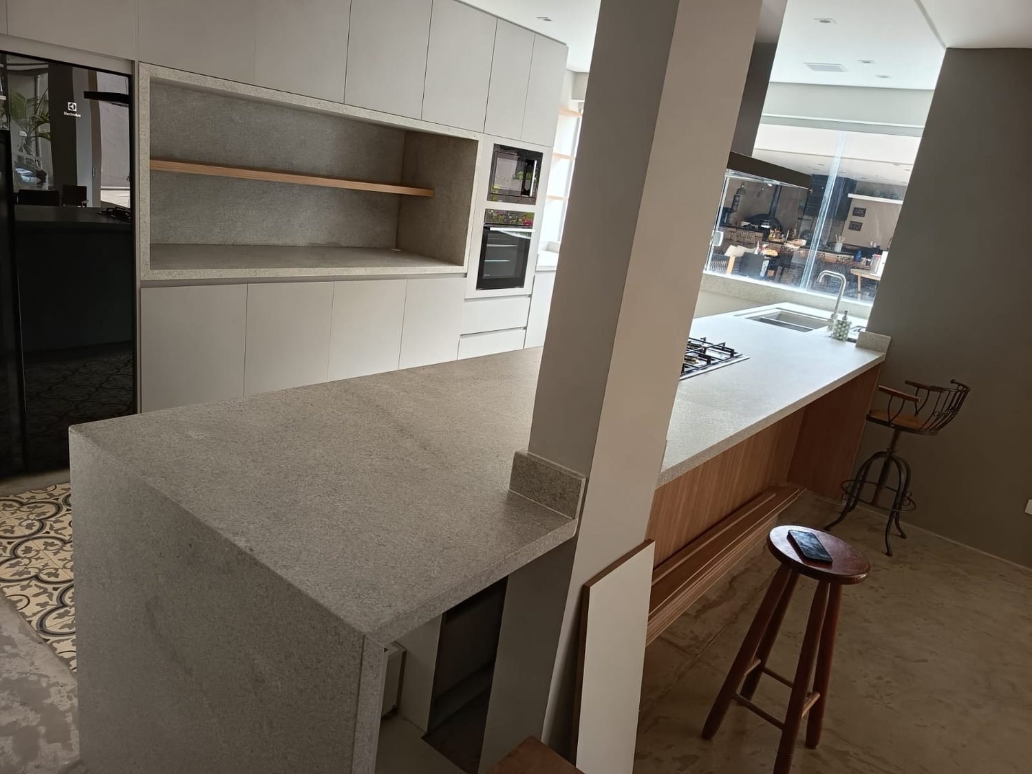 Cozinha com nicho revestido em granito cinza e bancada com lateral em cascata