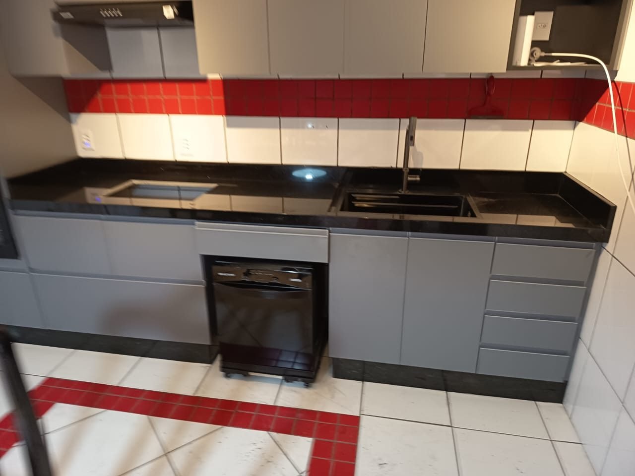Cozinha com bancada em granito preto polido, cuba embutida e armários cinza