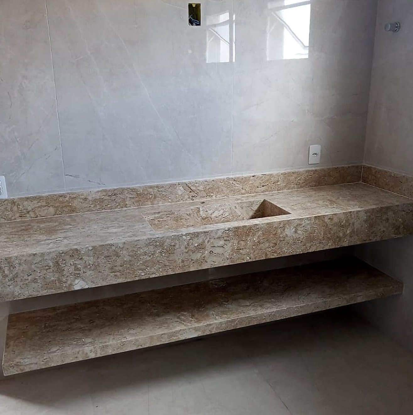 Lavatório em mármore travertino com cuba esculpida e prateleira em pedra